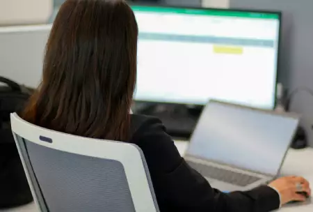 Mulher sentada ao computador a registar números em Excel